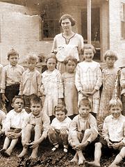 Teacher and students outside their one-room schoolhouse. Many poor families had to choose between buying their children shoes or school books.
