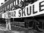Huey Long standing in front of a train of Louisiana State University students on their way to a football game. 'Ole War Skule' is a reference to LSU's founding as a military academy after the Civil War.