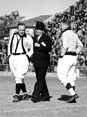 Huey Long on the gridiron with referees before a Louisiana State University football game.